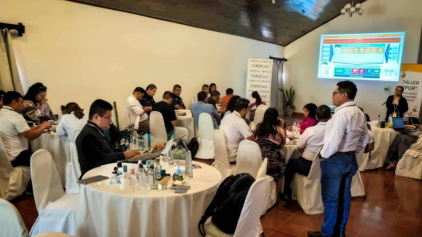 Meetings That Actually Work Corporate training session in progress with participants at round tables and presentation screen at Ancestral Copán Hotel conference room